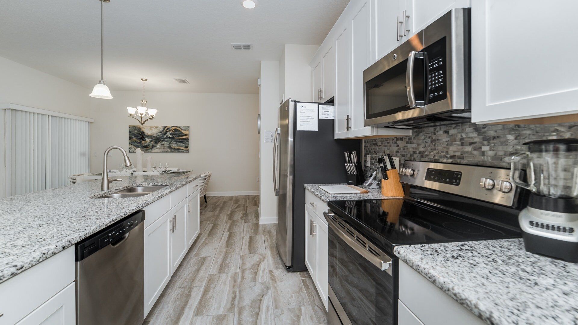 A modern kitchen with granite countertops, stainless steel appliances, and a backsplash.