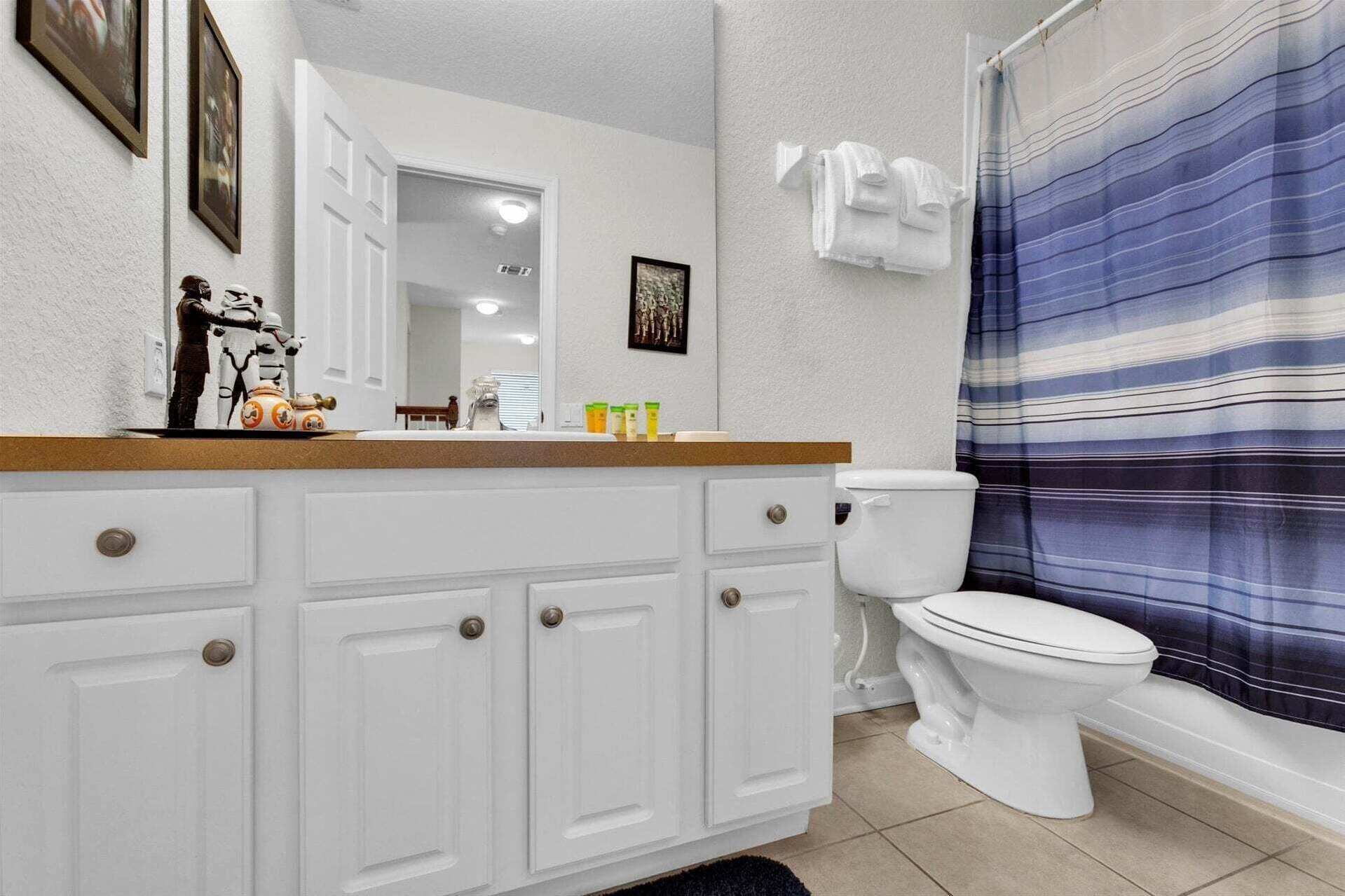 A bathroom with a white toilet, a striped shower curtain, and a sink with a mirror above it.