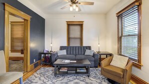 A living room with a gray sofa, a brown armchair, a coffee table, and a ceiling fan. - Historic Downtown Meets Modern Comfort (Colorado Springs)