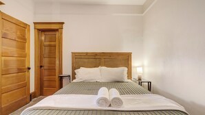 A neatly made bed with a striped bedspread, a wooden headboard, and two rolled towels placed on the bed. - Historic Downtown Meets Modern Comfort (Colorado Springs)