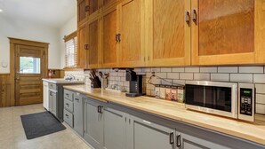 A kitchen with wooden cabinets, a microwave, and a coffee maker. - Historic Downtown Meets Modern Comfort (Colorado Springs)