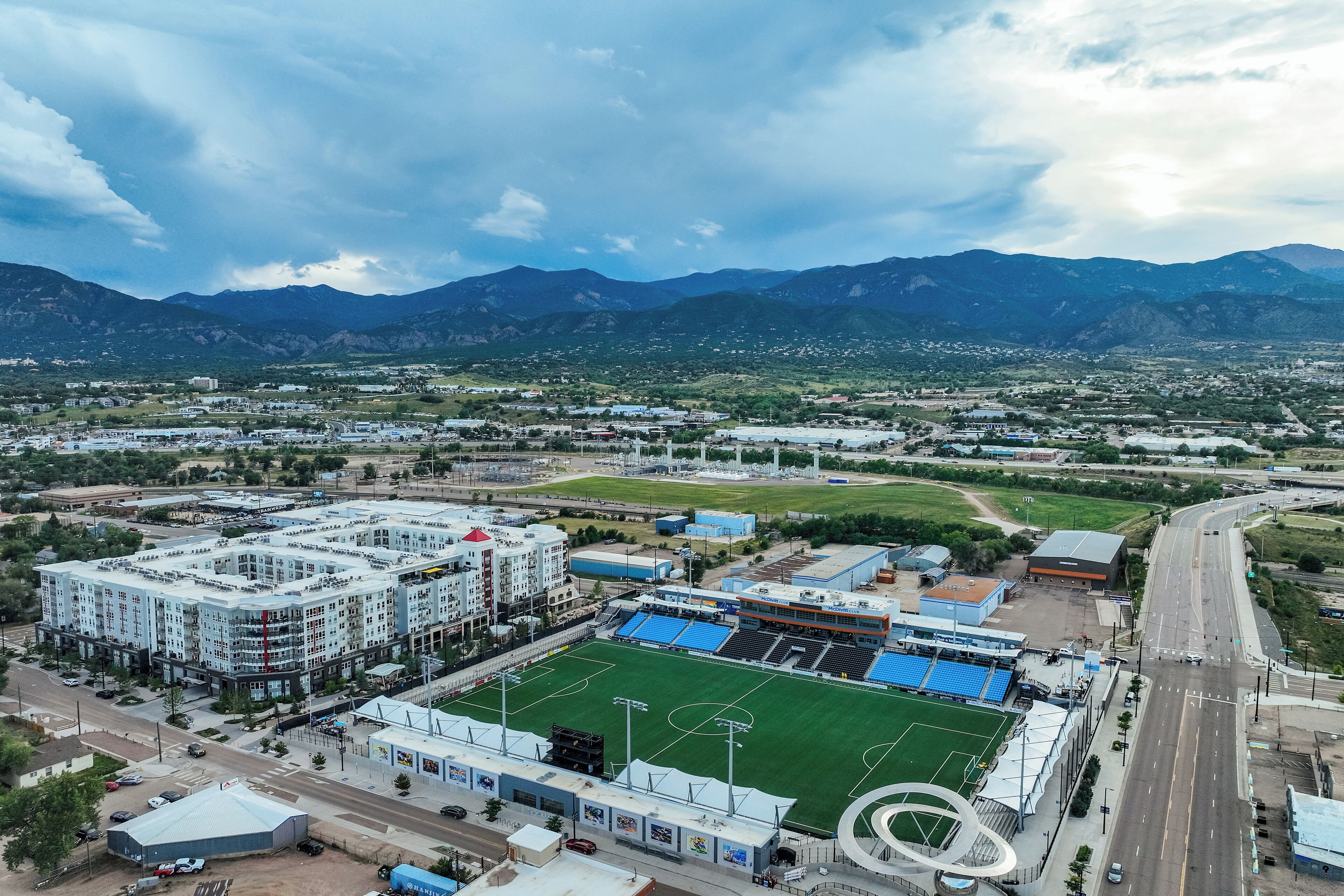 Vue aérienne d’un complexe sportif comprenant un stade, des bâtiments et une route.