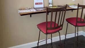 A room with a dining table, two red chairs, a wall-mounted artwork of bamboo forest, a 'No Smoking' sign, and a small shelf with brochures. - Bright Modern Loft for Adventurers (Roanoke)