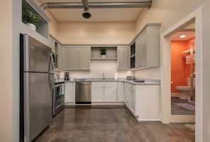 A modern kitchen with stainless steel appliances, white cabinetry, and a central island. - Bright Modern Loft for Adventurers (Roanoke)
