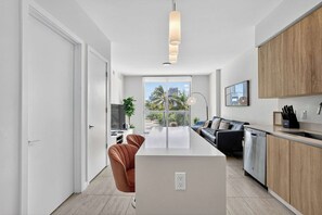 Une cuisine moderne dotée d’un îlot central, de meubles en bois et offrant une vue sur l’extérieur.