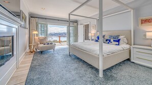 Ein Bett mit Baldachin mit Blick ins Freie, ein Kamin und ein großes Fenster.