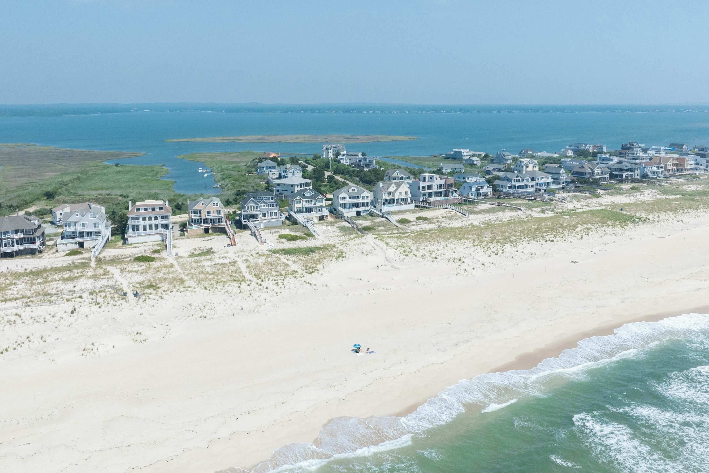 Uma área residencial costeira com propriedades à beira-mar, uma praia de areia e vista para o oceano.