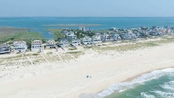 Uma área residencial costeira com propriedades à beira-mar, uma praia de areia e vista para o oceano.