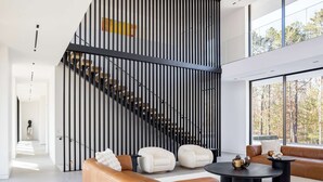 Un interior moderno con una escalera, sofás de cuero y un ventanal grande.