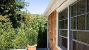 Eine Holzfassade mit Fenster, einem Blumentopf und einer Metall-Dusche.