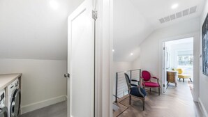 Eine moderne Wohnung mit Waschbereich, einer Treppe zu einem Wohnbereich mit Blick und einem Essbereich mit bunten Stühlen.