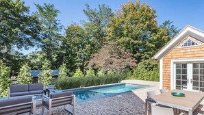 Ein Garten mit Swimmingpool, Gartenmöbeln und einem Holzhaus.
