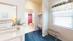 Une chambre à coucher avec un lit, une plante en pot, un miroir et une fenêtre avec des stores.