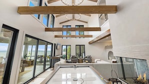 A spacious room with a large window, a fireplace, and a pool table. - Waterfront Retreat on West Bay w Hot Tub, Games & More! 7345 (Traverse City)
