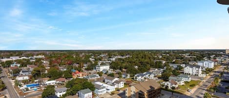 An aerial view of a residential area with houses, streets, and a clear sky.