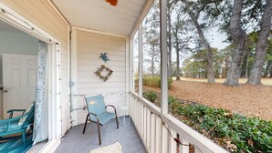 A porch with a rocking chair, a small table, and a wreath on the wall. - River Creek 2 Unit 1802 (Sunset Beach)