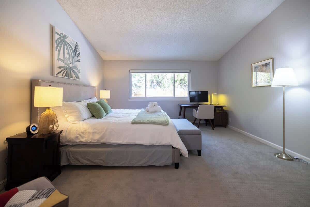 A bedroom with a bed, bedside tables, a desk, and a chair.