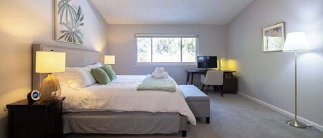 A bedroom with a bed, bedside tables, a desk, and a chair.