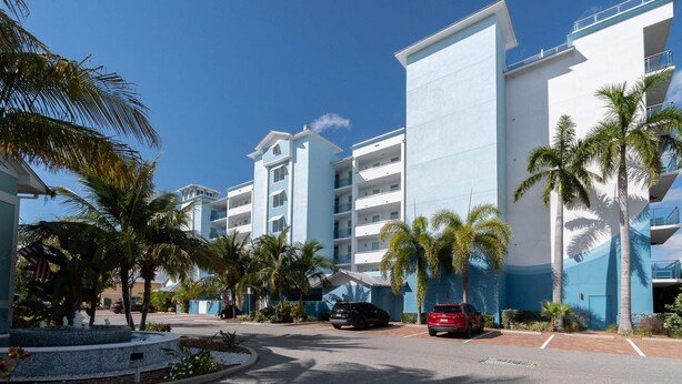 Un hôtel à plusieurs étages, doté d’une architecture moderne, avec des balcons et un parking pouvant accueillir plusieurs voitures.