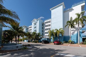 A multi-story hotel with a modern design, featuring balconies and a parking area with several cars. - Waterfront Stateroom (Merritt Island)