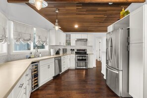 Une cuisine moderne avec des armoires blanches, des appareils en acier inoxydable et un plafond en bois.