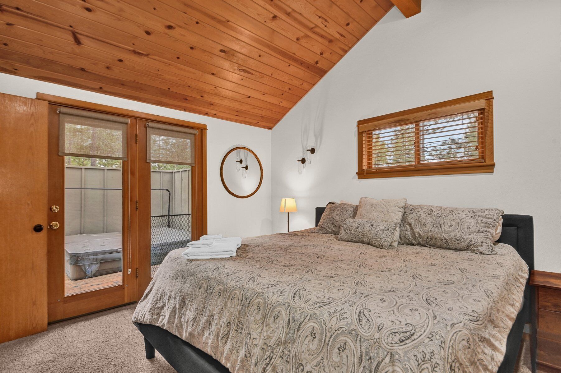 Quarto com cama, janela, porta e luminária fixada na parede.