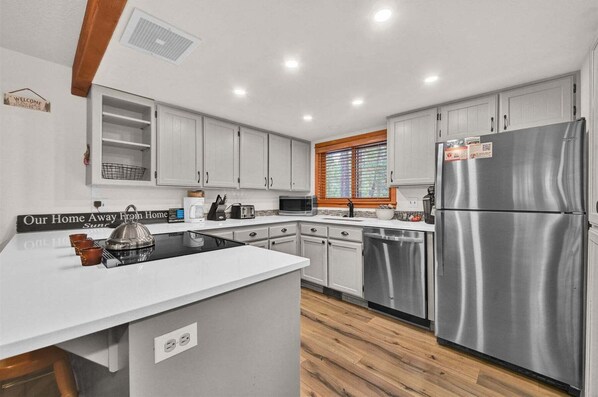 Una cucina moderna con mobili bianchi, elettrodomestici in acciaio inossidabile e pavimento in legno.