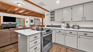 A modern kitchen with white cabinets, a built-in oven, and a coffee maker. - Otter Hot Tub Retreat Near Sharc (Bend)