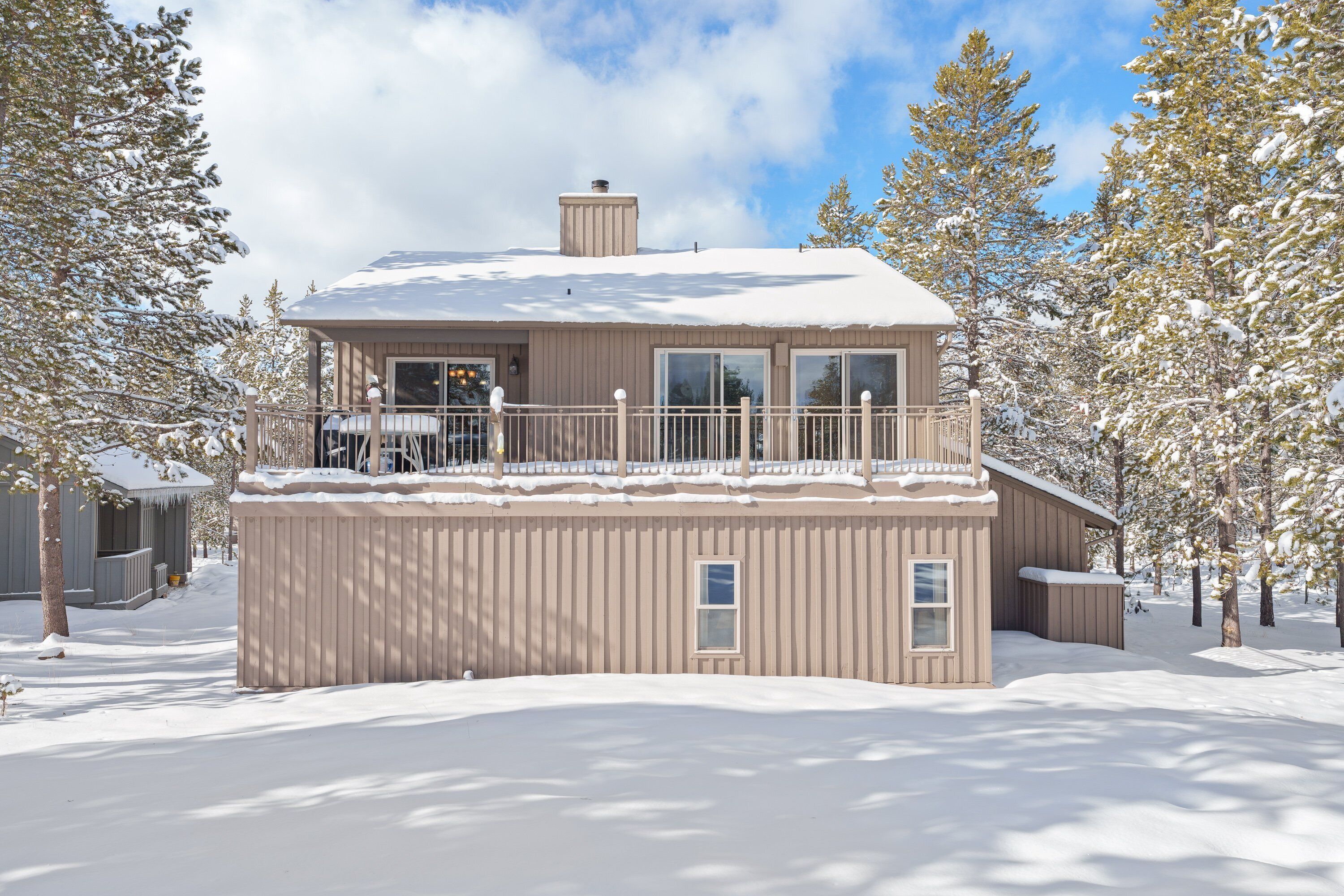A two-story building with a balcony, surrounded by snow-covered trees.