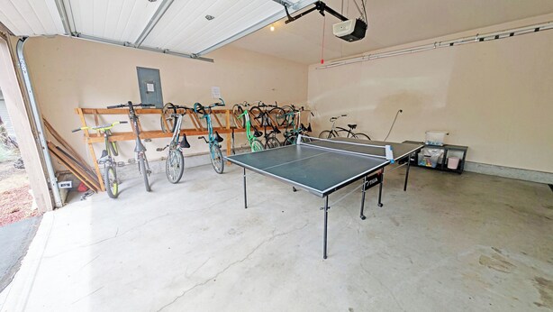 Un garage équipé d’une table de ping-pong, de vélos et d’un projecteur.