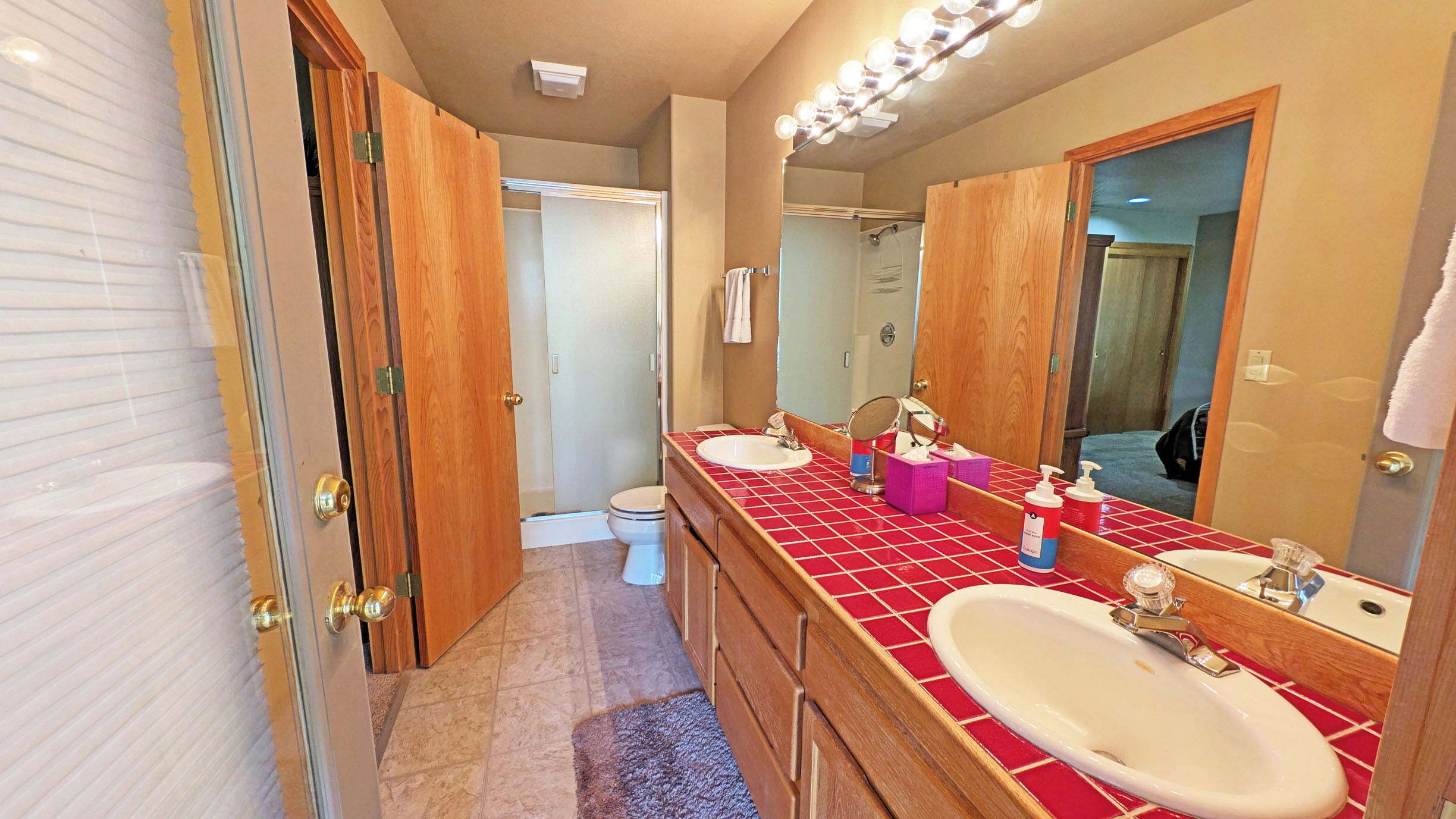 A bathroom with two sinks, a mirror, and a shower.