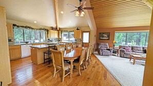 Une cuisine spacieuse avec des meubles de rangement en bois et un coin repas comprenant une grande table et des chaises en bois. Il y a également un salon avec un canapé et une table basse.