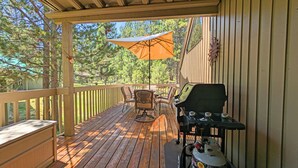 A wooden deck with a grill, outdoor furniture, and a large umbrella. - East Butte 14 (Bend)