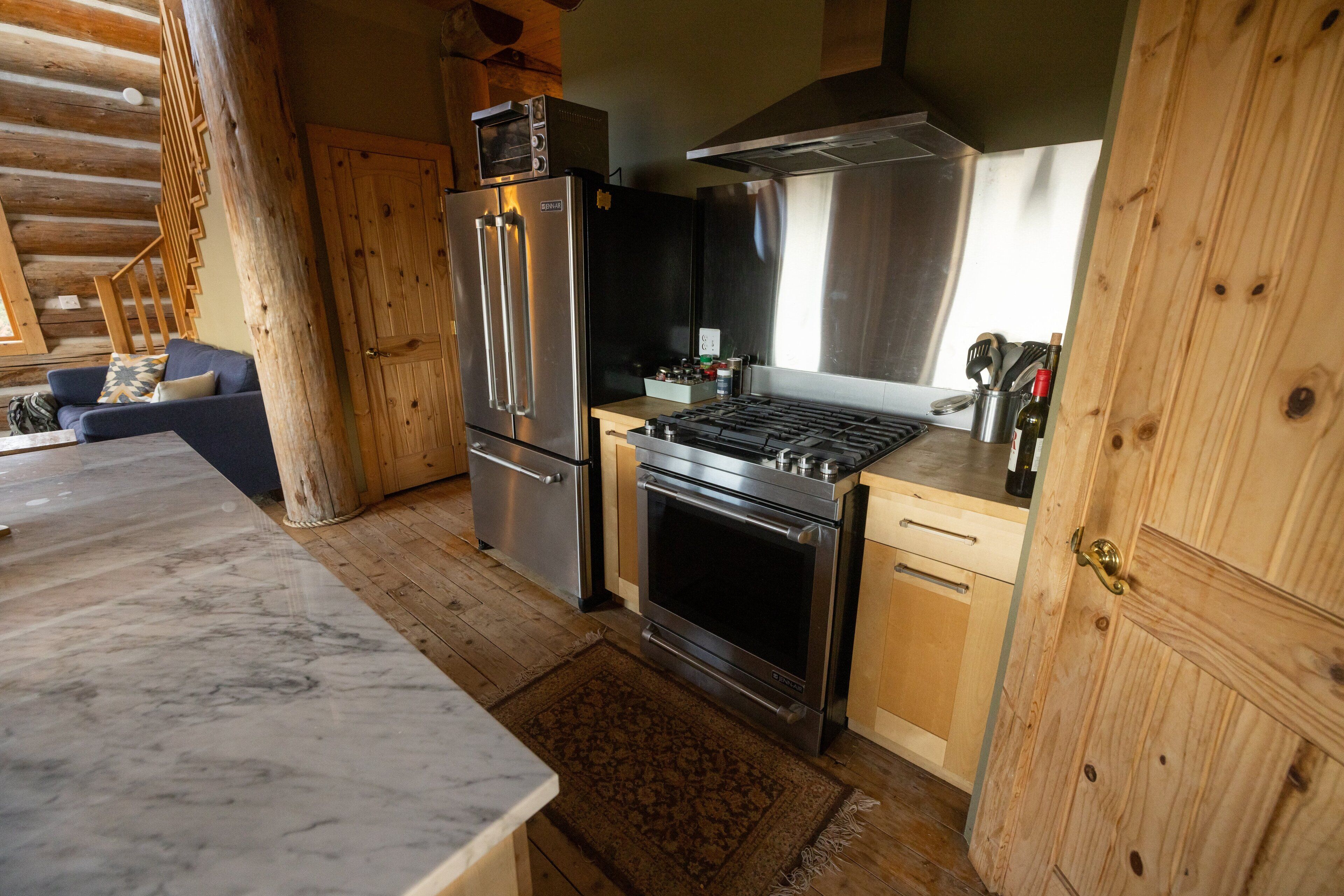 A modern kitchen with stainless steel appliances, wooden cabinets, and a marble countertop.