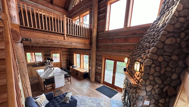 A log cabin interior with a dining area, a stone fireplace, and a cozy seating area. - Mosier Cabin Hot Tub Mt Adams View (The Dalles)