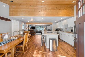 A spacious kitchen with wooden flooring, white cabinets, and a central island with stools. - Sunriver Hot Tub Home With Sharc Passes (Bend)