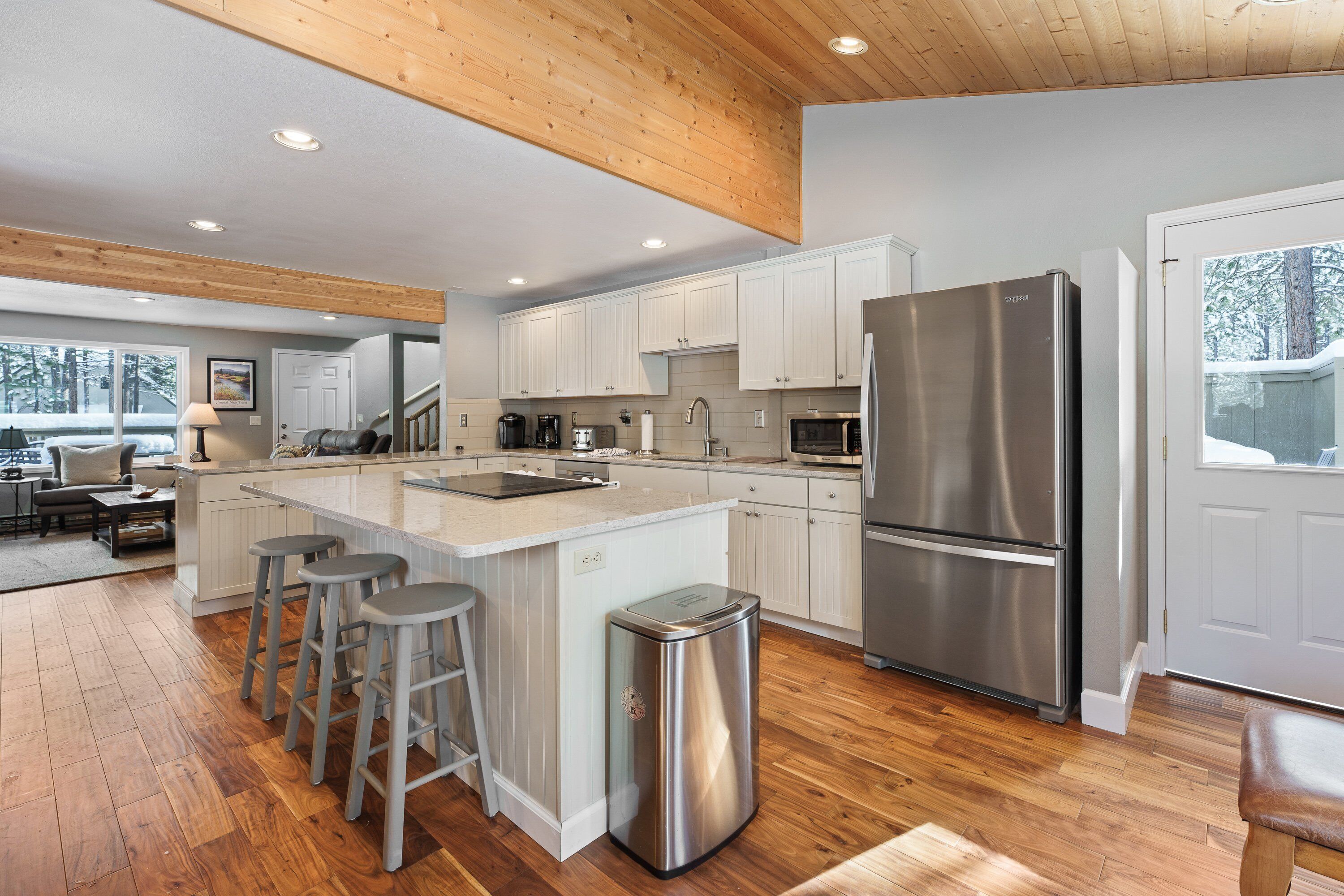 A modern kitchen with a large island, stainless steel appliances, and wooden flooring.