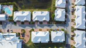 An aerial view of a residential area with multiple houses, a swimming pool, and a road. - Stateroom Elite (Merritt Island)