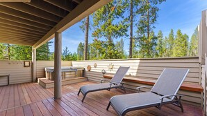 A covered outdoor deck with two lounge chairs, a table, and a bench. - Sunriver Golf Views Hot Tub Escape (Bend)