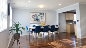 Un comedor con una mesa y sillas, una planta en maceta y un cuadro en la pared.