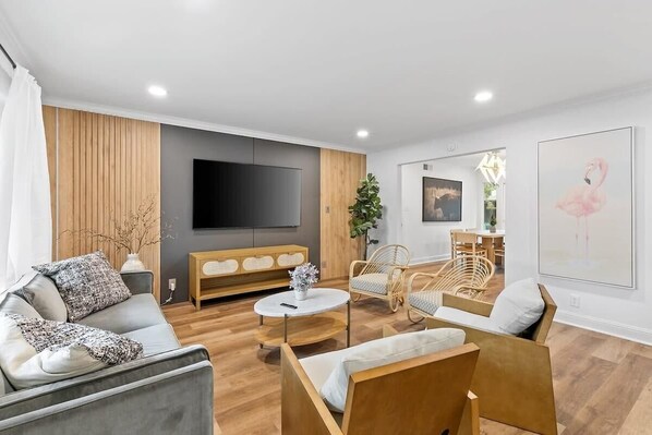 A modern living room with a grey sofa, a wooden coffee table, wicker chairs, and a flat-screen TV mounted on the wall. - Marbella Lane - Modern 3broasis in Siliconvalley (San Jose)