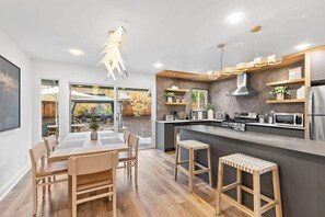 A modern kitchen with a central island, wooden chairs, and a dining table. - Marbella Lane - Modern 3broasis in Siliconvalley (San Jose)