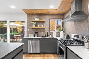 A modern kitchen with a built-in dishwasher, a stove, and a coffee maker. - Marbella Lane - Modern 3broasis in Siliconvalley (San Jose)