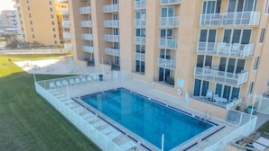 A rooftop swimming pool with white railings and lounge chairs, surrounded by a high-rise building with balconies. - Oceania Beach Club 203 (New Smyrna Beach)