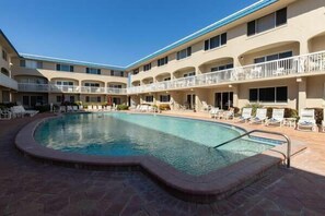 A hotel with a swimming pool, multiple balconies, and lounge chairs. - Win-san C315 (New Smyrna Beach)