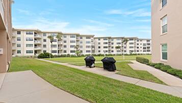 A residential building with multiple balconies, a well-maintained lawn, and a clear sky.