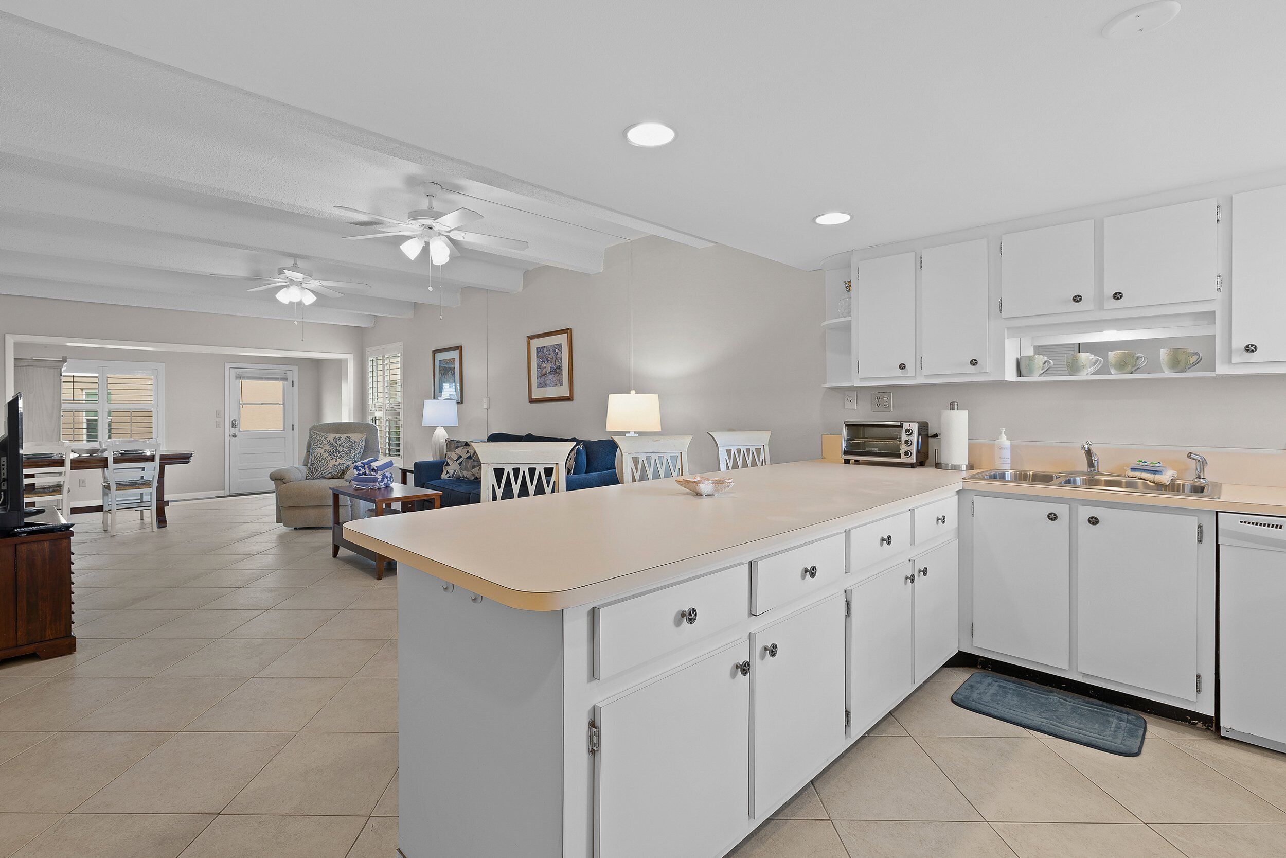 A spacious kitchen with white cabinets, a central island, and a dining area with a sofa and table.