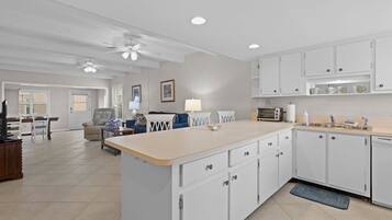 A spacious kitchen with white cabinets, a central island, and a dining area with a sofa and table.