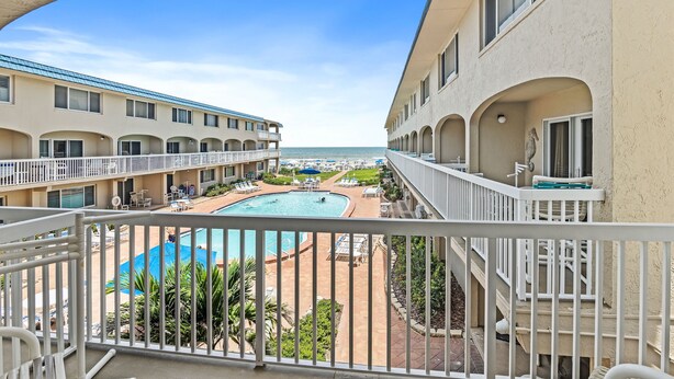 A hotel with a pool area, multiple balconies, and a view of the ocean.