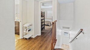 A spacious room with hardwood flooring, a wooden staircase, and a white wall.